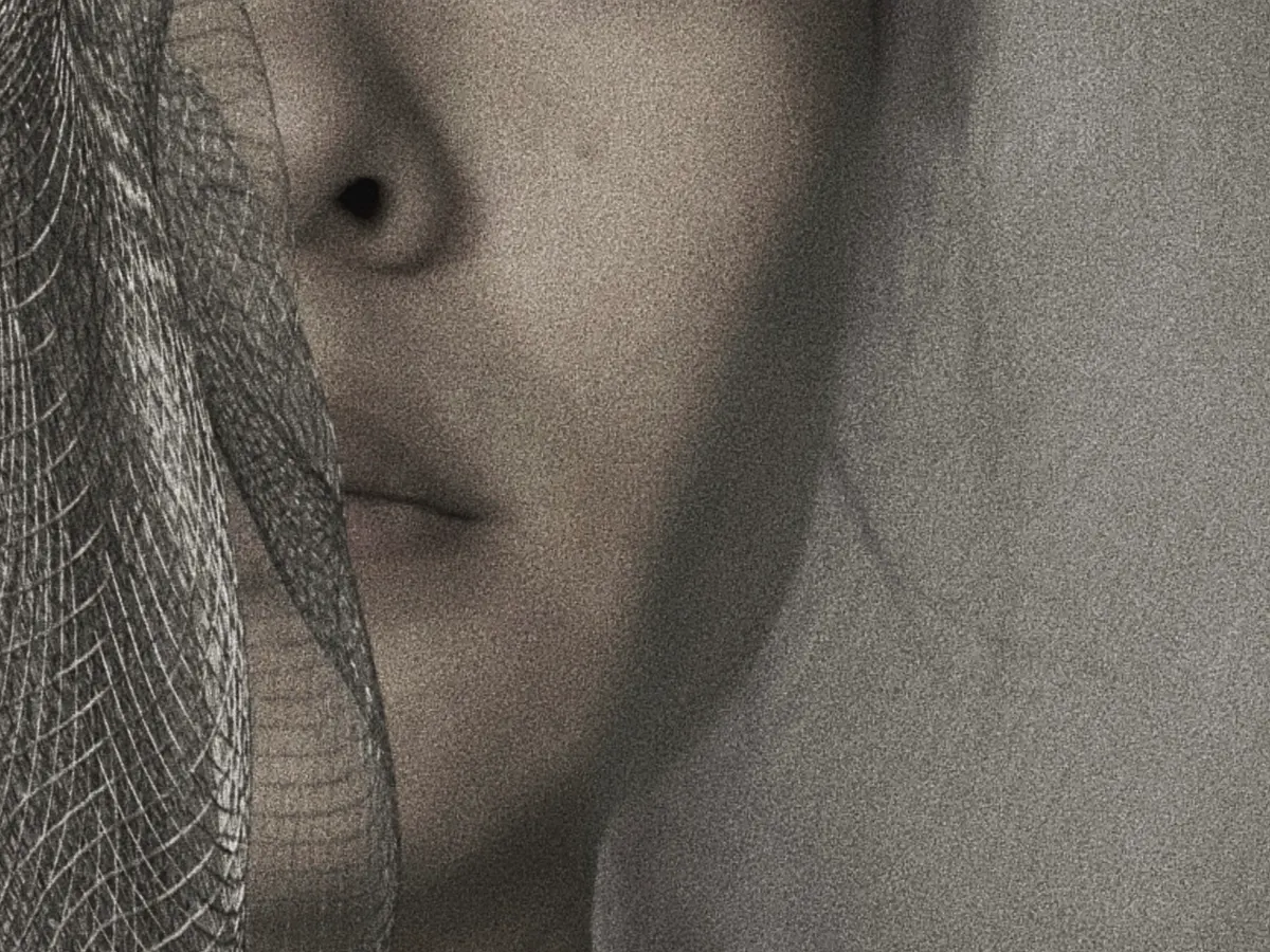 Close-up of a face partially obscured by metal mesh.