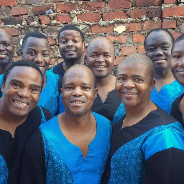 A group of gospel singers wearing black gowns with bright blue collars.