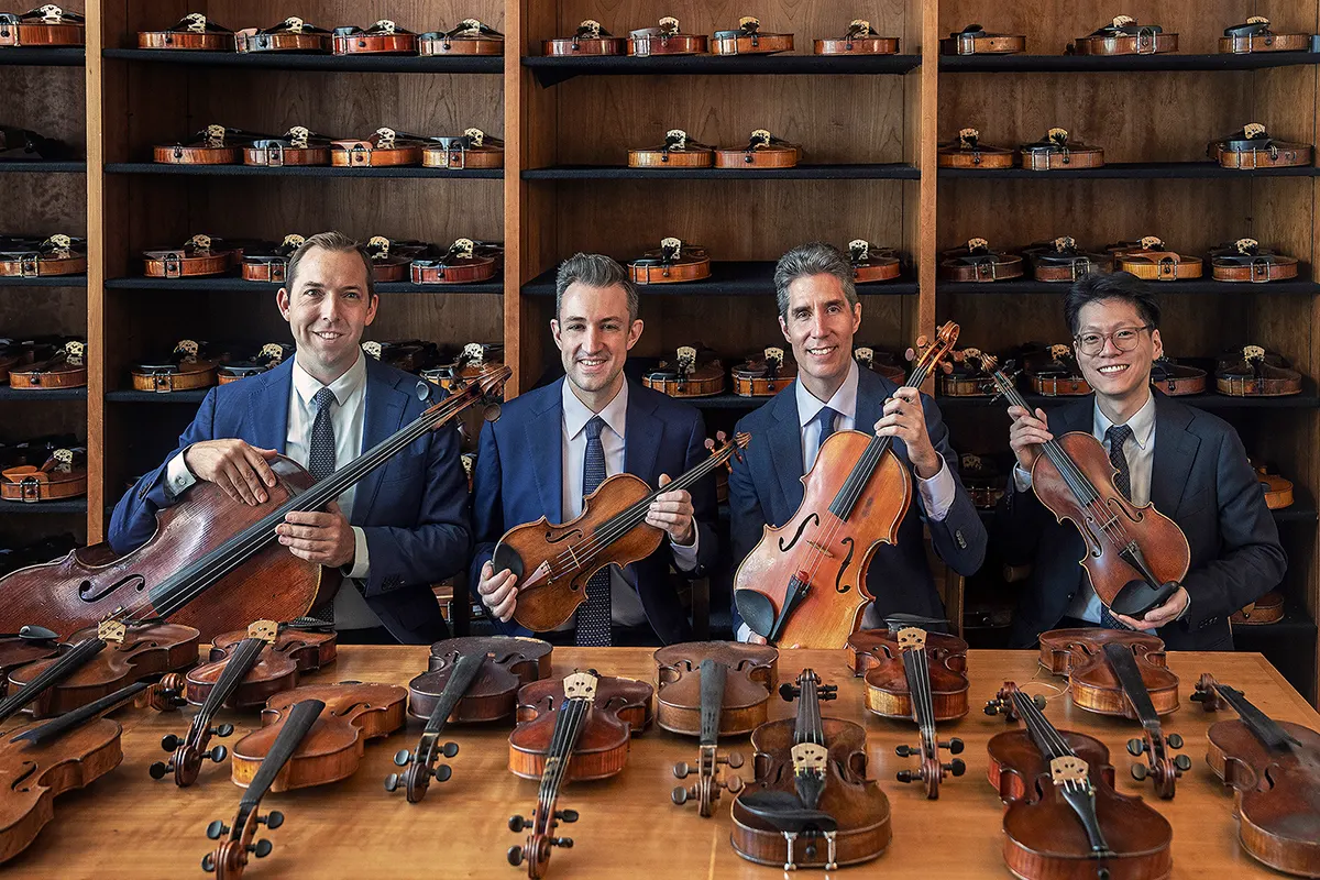 Four male musicians in suits, with 2 violins, a viola and a cello