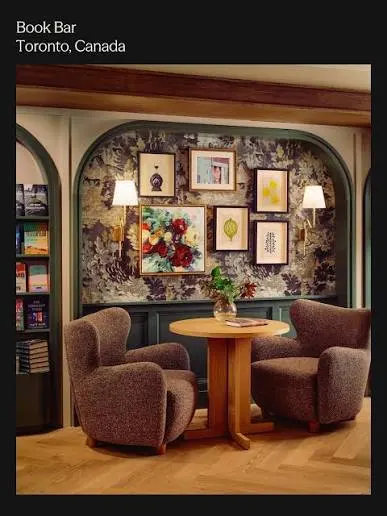two couch chairs sit on a decorated room filled with books.
