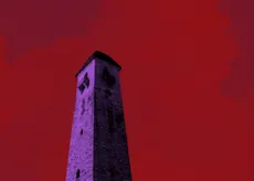 A red cloudy sky over purple rolling hills and a crumbling brick tower.