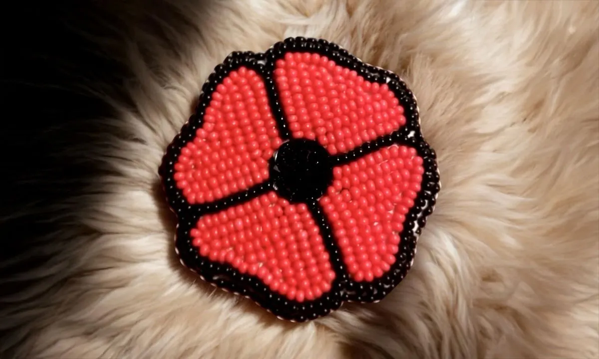 Beaded red poppy flower pin on a bed of light colour fur.