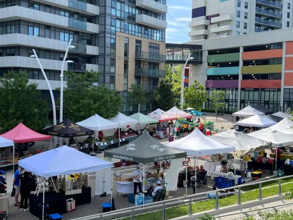 famers' market set up with tents in a square surrounded by apartment buildings.