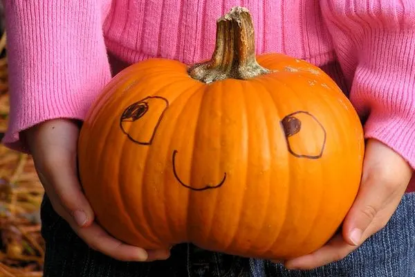 holding a smiley pumpkin