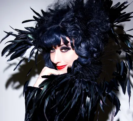 A woman dressed in all black, with a feathered boa around her.