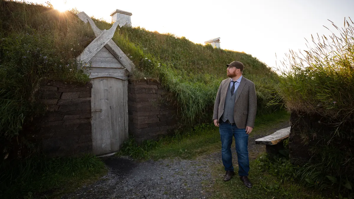 Man standing in front of wooden doorway with green grass roof