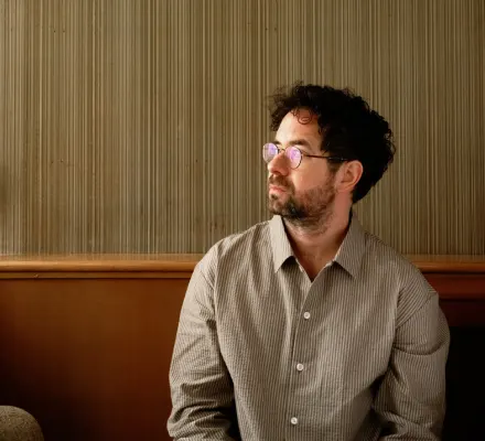 Jean Michel Blais looks to his right. He wears a casual linen shirt.
