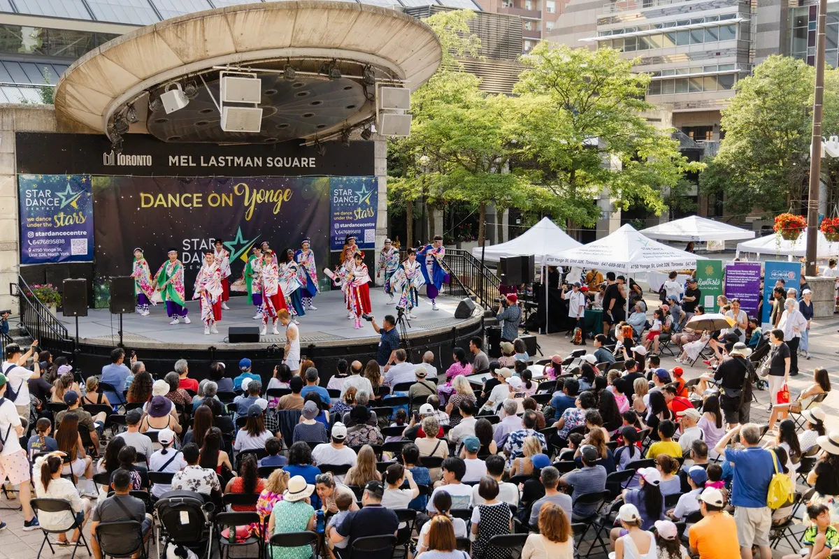 Crowd watching a colourful outdoor dance performance at Dance on Yonge in Mel Lastman Square.