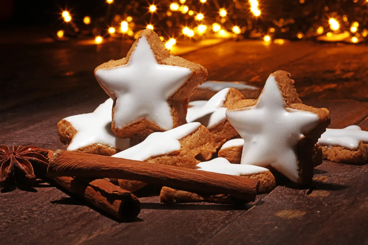 Iced star shaped gingerbread cookies with twinkling lights in the background
