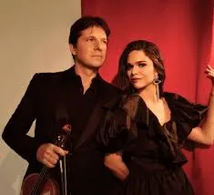 Joshua Bell and Larisa Martínez, lean against each other. They both wear black.